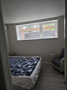 Fotografi av et soverom med seng, armstol og vindu.