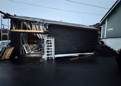 Fotografi av en bygning (garasje eller uthus) under ombygging eller reparasjon, med synlig takkonstruksjon og byggematerialer.