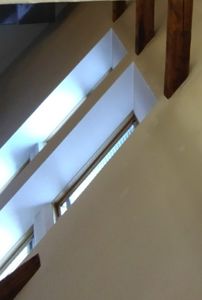 Fotografi av et takrom med skråtak, trebjelker og taklyster.