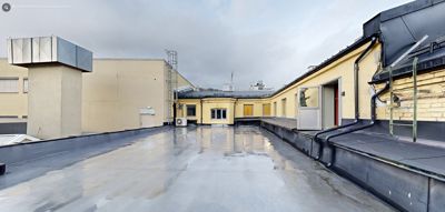 Fotografi av et takterreng med gulmalt fasade, ventilasjonsutstyr og nedløp.