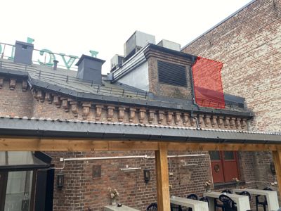 Fotografi av en bygning sett fra nede, som viser fasade, takkonstruksjon og utendørs terrasse.