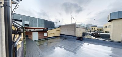 Fotografi av et takterreng eller en flat takflate sett fra utsiden, med omgivende bygninger og kraner i bakgrunnen.