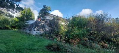 Fotografi av en bygning plassert på en steinete bakke, omgitt av vegetasjon.