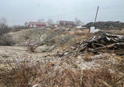 Fotografi av et snødekt område med en bygning i bakgrunnen og en haug med skrot i forgrunnen.
