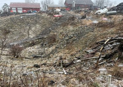 Fotografi av et utendørs område med en bygning i bakgrunnen, snø på bakken og spredt avfall.