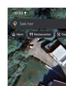 Satellittbilde fra Google Maps som viser en tomt med en bygning og en markert sirkel.