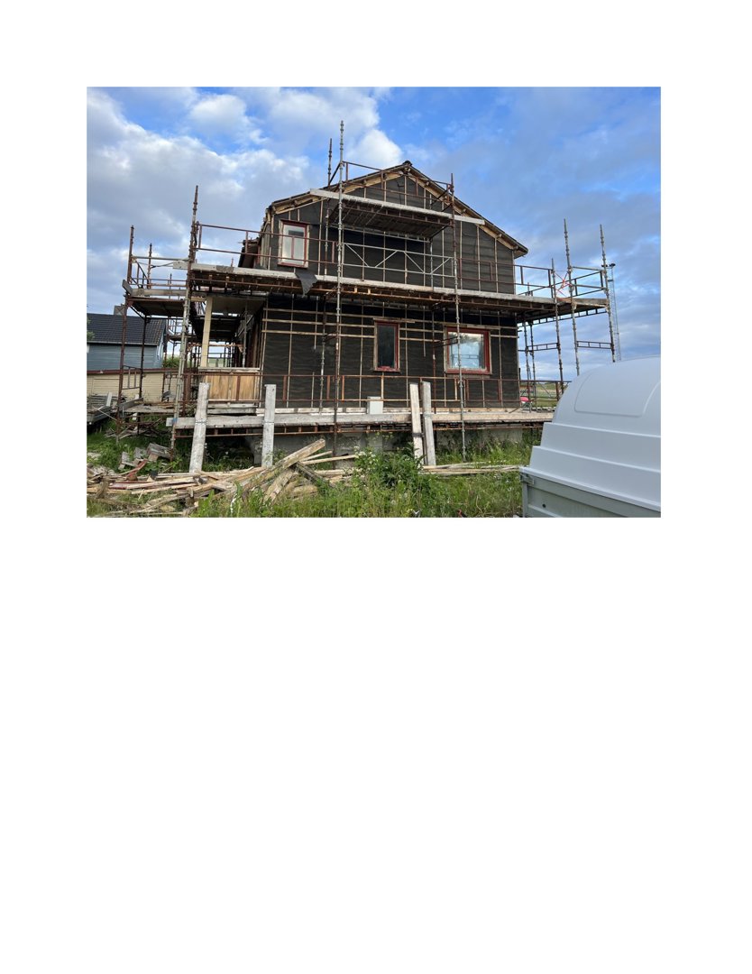 Fotografi av en toetasjes bolig under bygging, med stålscaffolding rundt huset og en grå container i forgrunnen.