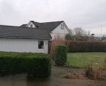 Fotografi av en hvit villa med grønt hageområde.