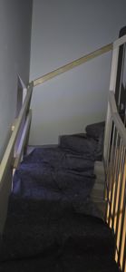 Fotografi av en trapp med mørke trinn, lys håndtak og metallstenger.