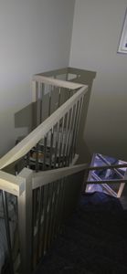 Fotografi av en trapp med lys trelist og metallstenger, sett fra øvre etasje nedover.