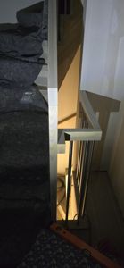 Fotografi av en trapp under bygging eller ombygging, med synlig tretrinn, metallrailing og byggematerialer.