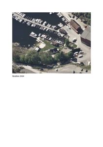 Luftfoto (dronefoto) av et område med båthavn, båter, og bygninger ved kysten.