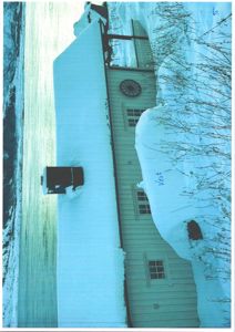 Fotografi av en bygning (trollmannsbolig) sett fra siden, med store snøhoper og et vindu.