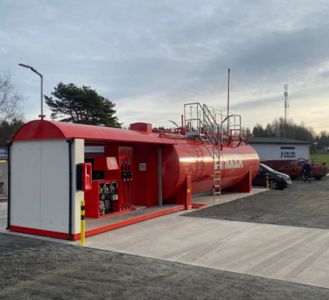 Fotografi av en rød gassstasjon med tank og betongplassering.