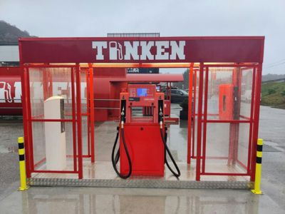 Fotografi av en rød bensinpumpe med vaskesystem (Tanken) på en bensinstasjon.