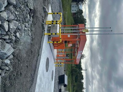 Fotografi av en nyinstallert bensinstasjon (TÜNKEN) på en tomme med grus og stein.