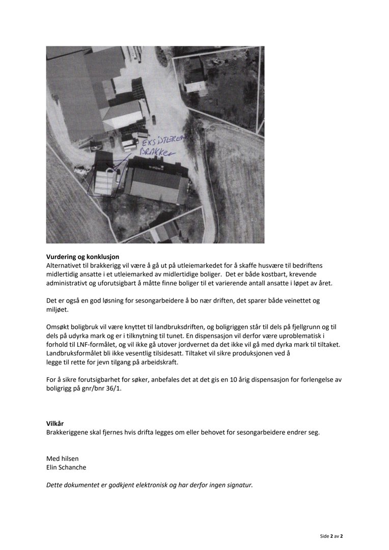 Et svart-hvitt fotografi tatt fra luften (flyfoto) som viser en tomt med flere bygninger, veier og omgivende terreng. Bildet har håndskrevne notater på det.