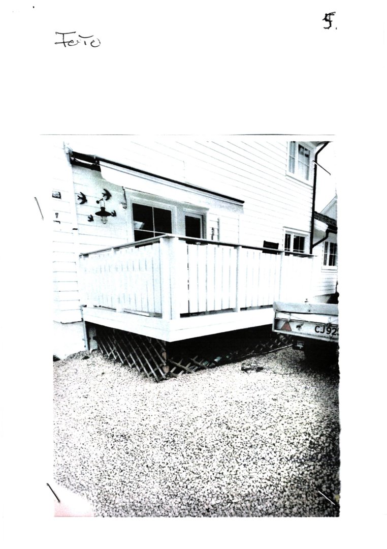 Fotografi av en terrasse med balustrade og en bil parkert ved siden av.