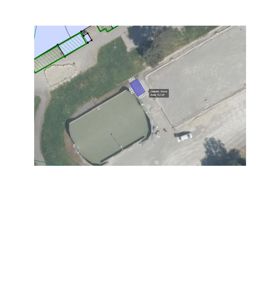 Situasjonsplan som viser en tomt med eksisterende bygninger (en stor grønn struktur og en mindre blå), samt en planlagt nybygning markert med et blått felt. Bildet inneholder også målinger for den nye bygningen.