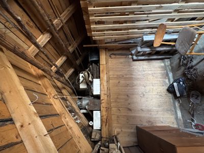 Fotografi av et innvendig rom, sannsynligvis et loft eller et underbygg, som er fylt med diverse gjenstander og utstyr.