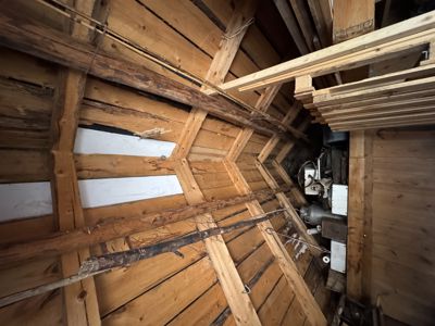 Fotografi av en eksisterende, gammel takkonstruksjon med tømmerbjelker og takplater.