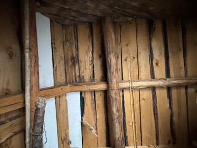 Fotografi av en gammel, rustikk trekonstruksjon, sannsynligvis takbjelker eller etasjeskiller i et hus.