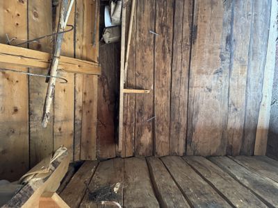 Fotografi av et gammelt, trepanelt rom, sannsynligvis et loft eller et underbygg, med synlig treverk og konstruksjonsdetaljer.