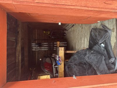 Fotografi av et innvendig rom, sannsynligvis en skur eller garasje, som inneholder ski, sykkel og andre gjenstander.