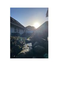 Fotografi av en eksisterende bolig med tilhørende hage og naboer sett fra bakgård eller sidehage.