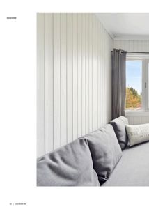 Fotografi av et soverom med hvite panelvegger, en grå sofa og et vindu.