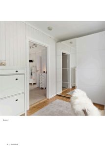 Fotografi av et innendørs rom, sannsynligvis et soverom, med hvite panelvegger, gulvbelegg og møbler.