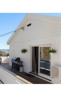 Fotografi av en hvit bygning sett fra utsiden, med en terrasse, grill og en luftavfukter.