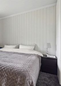 Fotografi av et soverom med en seng, nattbord og innredning.