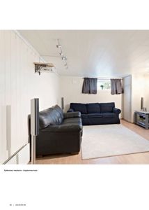 Fotografi av en innredet kjellerstue/mediarom med sofaer, gulvteppe og hvite panelvegger.