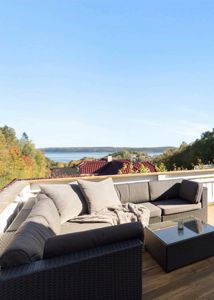 Fotografi av en terrasse med møbler og utsikt over vann og fjell.