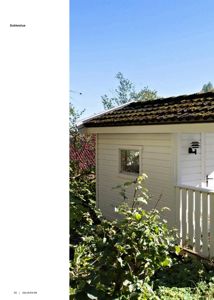 Fotografi av en liten hvit bygning (dukkestue) i en hage.