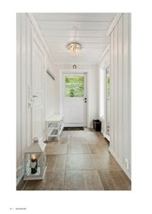 Fotografi av en innvendig gang i en bolig med hvite panelvegger, flisgulv og en hvit inngangsdør.