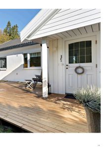 Fotografi av en hvit villa med en nybygd treterrasse og en hvit dør med vindue.