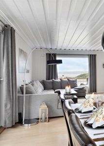 Fotografi av et innredet stue- og spisestueområde med utsikt over havet.