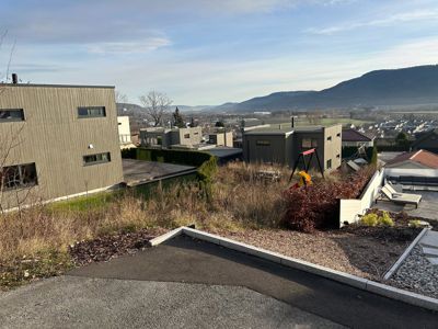 Fotografi av en moderne boligbebyggelse med fjell i bakgrunnen.