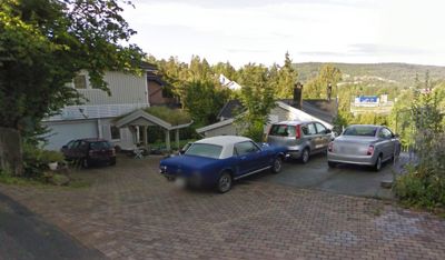 Fotografi av en bolig med flere parkerte biler på en flislagt kjørekai.