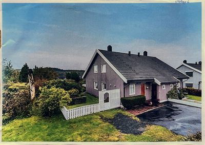 Fotografi av en liggende villa med gresshage, hagestue og hvit hekk sett fra et høyere nivå.