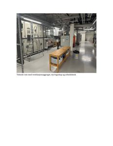 Fotografi av et teknisk rom inne i en bygning, som viser ventilasjonsaggregat, styringsskap og arbeidsbenk.