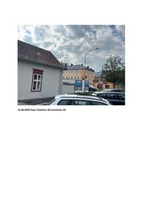 Fotografi av en gateløp med en grå bygning i forgrunnen og en gul bygning i bakgrunnen.