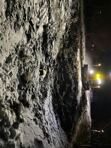 Fotografi av en byggeplass om natten med snø på bakken og en graver som arbeider.