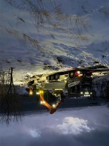 Fotografi av en byggeplass i snø ved kysten, med en lastebil og en graver som laster opp jordsmonn.