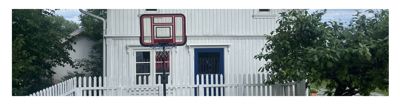 Fotografi av en hvit trehusfasade med en basketballkurve foran.