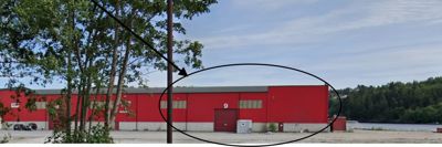 Fotografi av en rød industribygning sett fra utsiden, med et sirkel og pil som peker på en spesifikk del av fasaden.