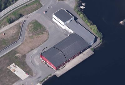 Luftfoto av en bygning med rødt fasade og grå tak, sett fra oven.