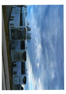 Fotografi av en bygning sett fra utsiden, med himmel og trær i bakgrunnen.